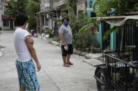 Christopher Bagay, left, a kitchen crew of the Aida Sol cruise ship in Europe, talks to his neighbor upon arriving at his home in Laguna province, south of Manila, Philippines Thursday, May 28, 2020. Bagay said it took him about two months to go through repetitive quarantines in Spain, Germany and Manila before he was finally allowed to go home. Tens of thousands of workers have returned by plane and ships as the pandemic, lockdowns and economic downturns decimated jobs worldwide in a major blow to the Philippines, a leading source of global labor. (AP Photo/Aaron Favila)