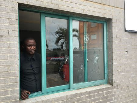 A man stands at a window with bullet holes at the headquarters of Gabon opposition leader Jean Ping which was destroyed after election related violence in Libreville, Gabon, September 19, 2016. REUTERS/Edward McAllister