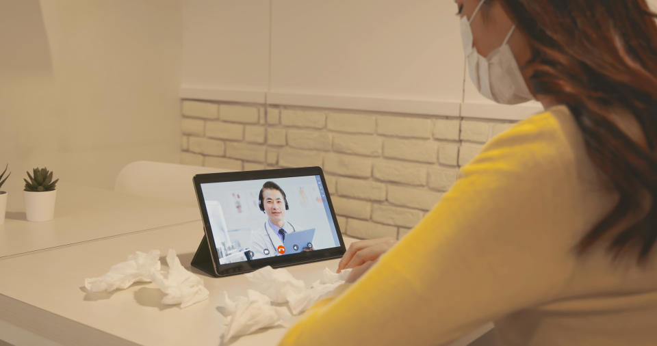 Telemedicine concept - asian woman patient is talking about her sick symptom to senior doctor by digital tablet at home