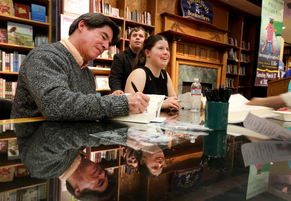 Paul Daugherty, Enquirer sports columnist, autographs his new book, "An Uncomplicated Life: A Father's Memoir of His Exceptional Daughter," at Joseph-Beth Booksellers  in Norwood in March 2015. The book chronicled he and wife, Kerry, raising their daughter, Jillian, at right, with Down syndrome.
