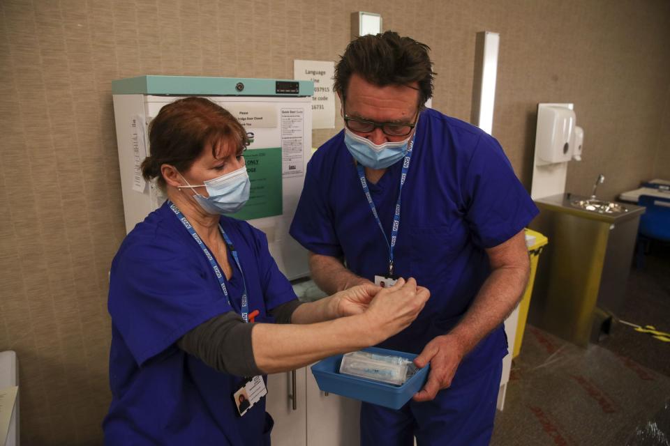 Gwendelina Duquette and Colin Pritchard prepare the Moderna Covid-19 vaccine at the vaccination centrePA