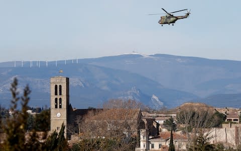 A military helicopter flies over the village of Trebes  - Credit: JEAN-PAUL PELISSIER /Reuters