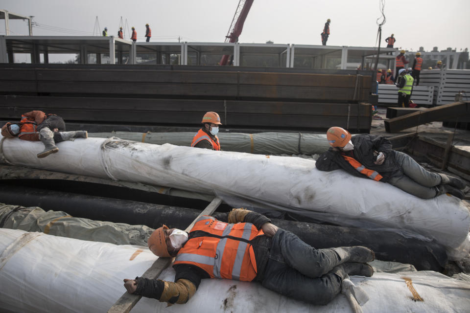 Construction workers rest on building materials as new hospitals are built to tackle the coronavirus.