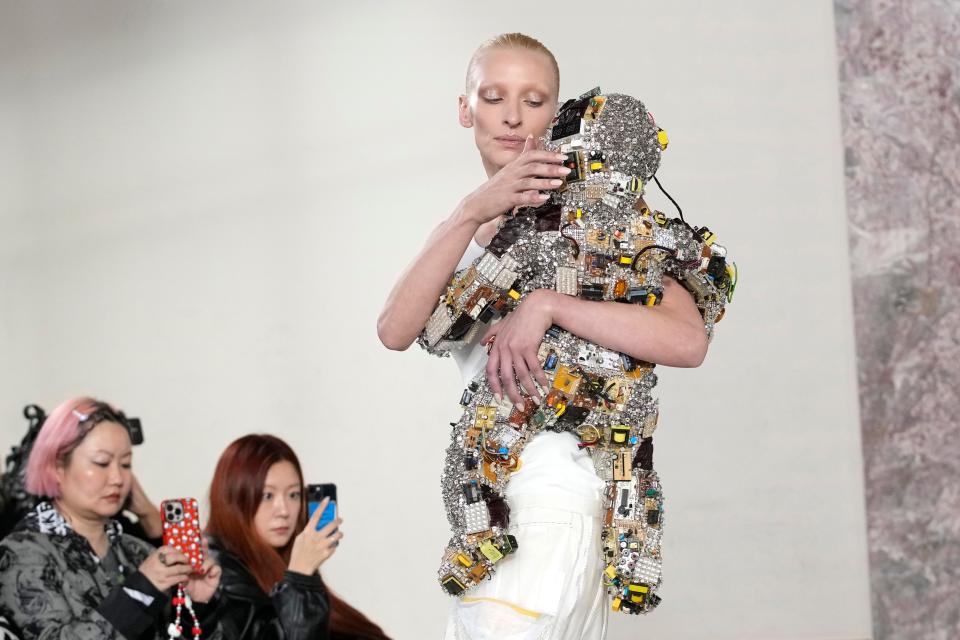 A model carries a toddler donned in Schiaparelli haute couture.