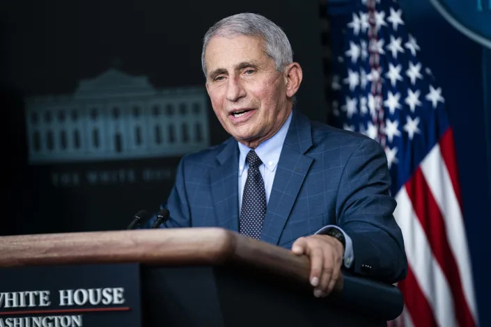 Dr. Anthony Fauci stands at a podium labeled White House in front of an American flag.