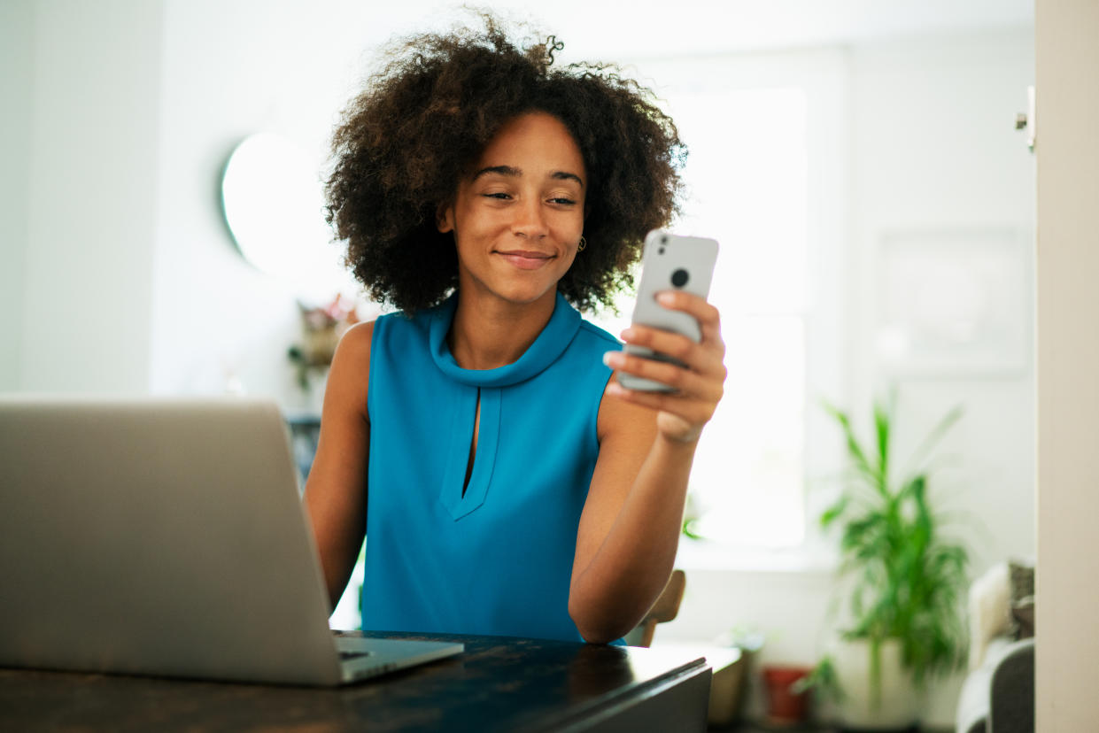 Woman using smart phone with laptop