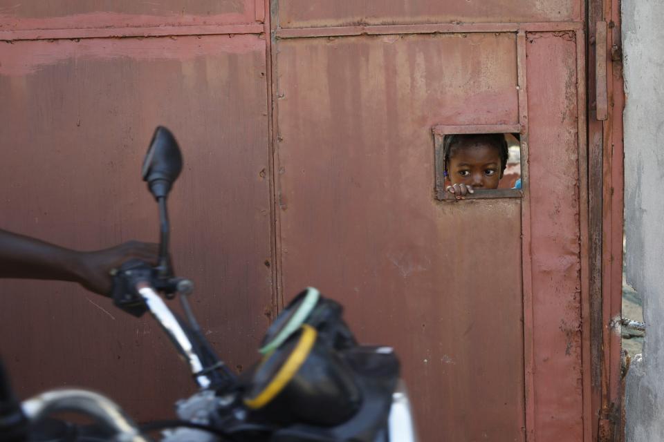 A child watches from an opening in a security gate as residents flee their homes due to gang violence, in Port-au-Prince, Haiti, Saturday, March 9, 2024. (AP Photo/Odelyn Joseph)