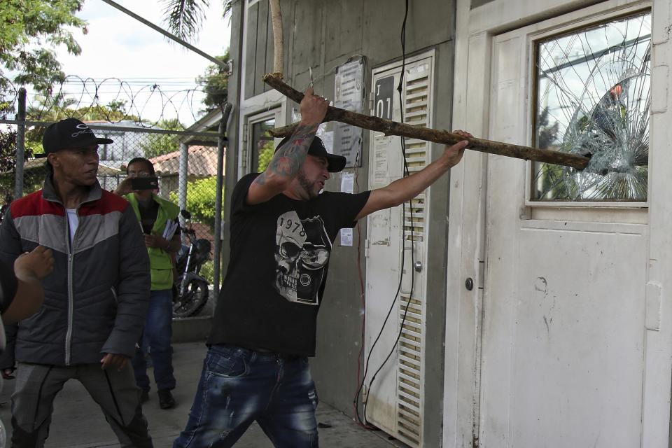 Inmates' relatives break a window at a prison where a deadly fire broke out in Tulua, Colombia, Tuesday, June 28, 2022. Authorities say at least 51 people were killed after the fire broke out during what appeared to be an attempted riot early Tuesday. (AP Photo/Andres Quintero)