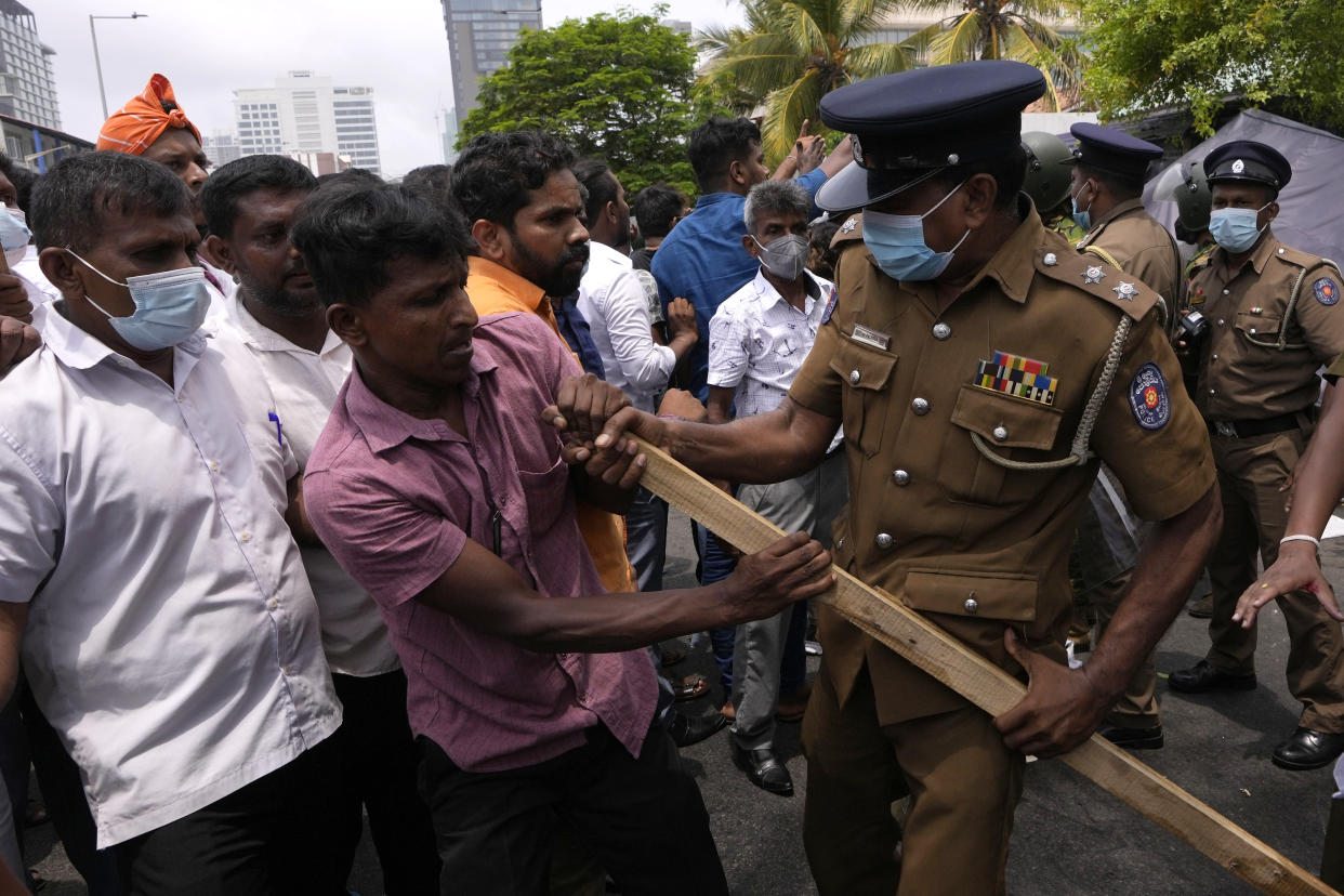 A Sri Lankan police officer tries to snatch a baton from a government supporter during clashes outside prime minister's residence in Colombo, Sri Lanka, Monday, May 9, 2022. Authorities deployed armed troops in the capital Colombo on Monday hours after government supporters attacked protesters who have been camped outside the offices of the country's president and prime minster, as trade unions began a “Week of Protests” demanding the government change and its president to step down over the country’s worst economic crisis in memory. (AP Photo/Eranga Jayawardena)