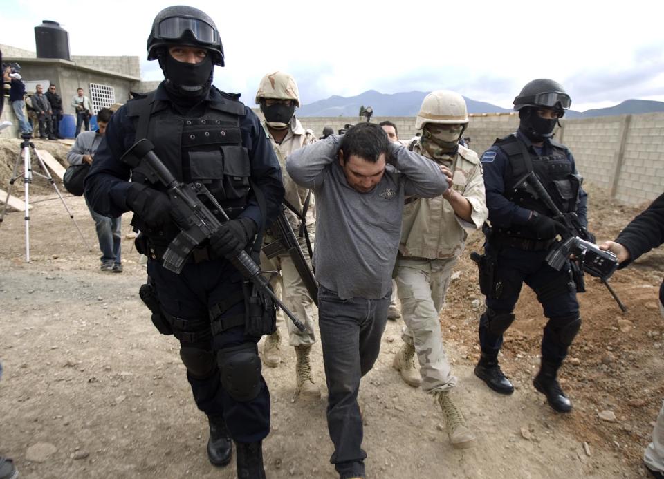 FILE - In this Jan. 23, 2009 file photo, Santiago Meza Lopez, 45, alias "El Pozolero del Teo," who allegedly worked for a drug lord from the Tijuana area, is escorted by soldiers and federal police agents during his arrest in Tijuana, Mexico.  Relatives of kidnap victims who never returned home are now finding out that their loved ones may have died at the hands of Santiago Meza, who admits he disposed of hundreds of victims by dissolving them in acid, according to documents obtained by The Associated Press. (AP Photo/Guillermo Arias, File)