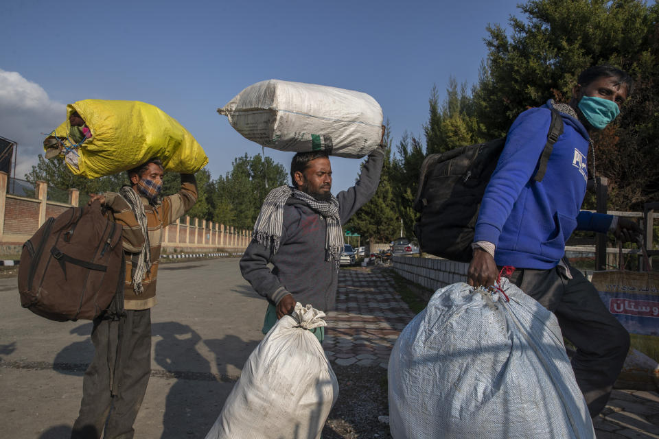 Indian migrant laborers carrying their belongings walk towards a railway station on the outskirts as they leave for their homes in Srinagar, Indian controlled Kashmir on Oct. 18, 2021. A spate of recent killings has rattled Indian-controlled Kashmir, with violence targeting local minority members and Indian civilians from outside the disputed region. Assailants shot and killed five Indian migrant workers this month increasing the death toll in targeted killings to 32 this year. (AP Photo/Dar Yasin)