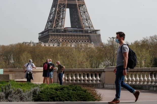 A man wearing a mask crosses the Bir Hakeim bridge in Paris, with the Eiffel Tower in the background, on April 1, 2021. U.S. tourists may be able to visit EU countries this summer if they are fully vaccinated.