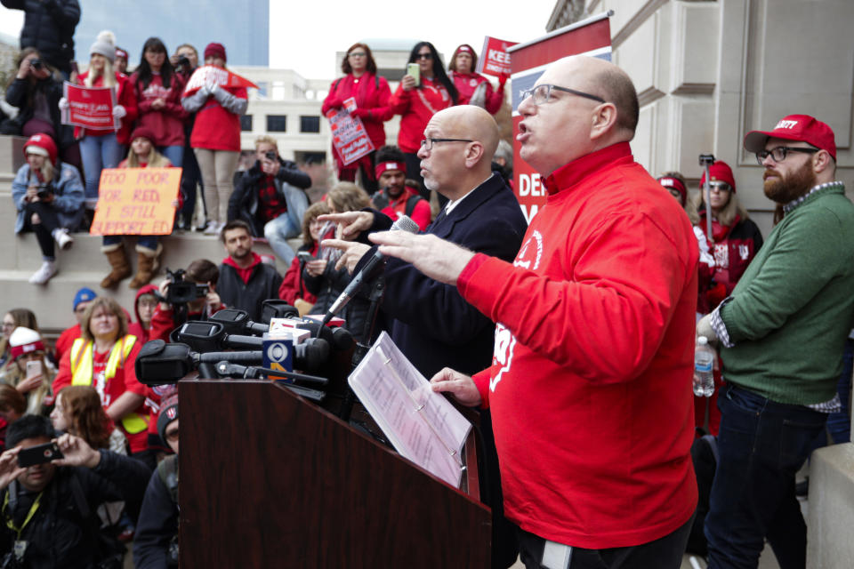 Keith Gambill, president of the Indiana State Teachers Association, of Evansville, Ind., speaks to the thousands of Indiana teachers wearing red as they surrounded the Statehouse in Indianapolis, Tuesday, Nov. 19, 2019 for a rally calling for further increasing teacher pay in the biggest such protest in the state amid a wave of educator activism across the country. Teacher unions says about half of Indiana's nearly 300 school districts are closed while their teachers attend Tuesday's rally while legislators gather for 2020 session organization meetings.(AP Photo/Michael Conroy)