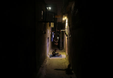 A Palestinian boy sits outside his family house as he escapes from the heat during a power cut, in Shati refugee camp, in Gaza City, July 2, 2017. The house is lit by battery-powered LED light bulbs. REUTERS/Mohammed Salem