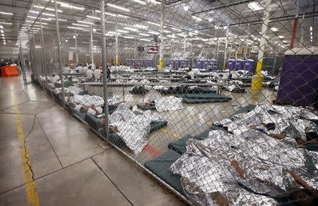 Detainees sleep and watch television in a holding cell where hundreds of mostly Central American immigrant children are being processed and held at the U.S. Customs and Border Protection (CBP) Nogales Placement Center in Nogales, Arizona, U.S. June 18, 2014. REUTERS/Ross D. Franklin/Pool/File Photo