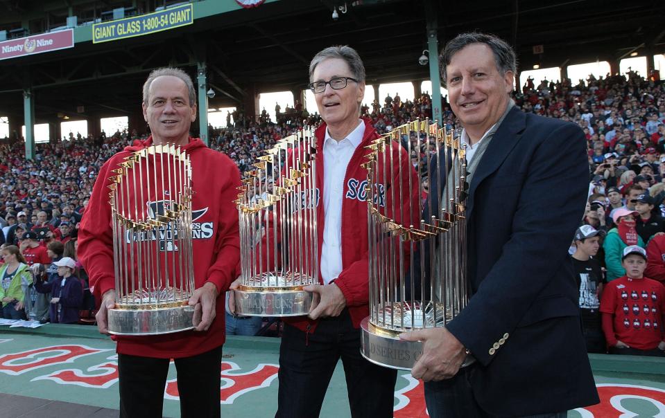 BOSTON, MA - NOVEMBER 2:  President and CEO of the Boston Red Sox Larry Lucchino, (left), Red Sox principal own John Henry (center), and Red Sox chairmanTom Werner show off the World Series trophies to the crowd at Fenway Park before the Red Sox players board the duck boats for the World Series victory parade for the Boston Red Sox on November 2, 2013 in Boston, Massachusetts.  (Photo by Gail Oskin/Getty Images)