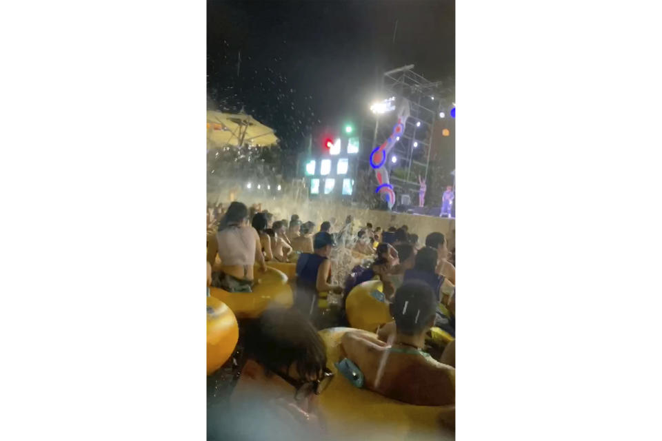 This image made from an Aug 3, 2020 video shows crowd gather in a pool as they watch performers on a stage at Wuhan Maya Beach Water Park in Wuhan, central China. For more than two months, the 11 million residents of Wuhan endured a strict lockdown as coronavirus raced around the city. Now, some are letting loose en masse at rocking nighttime pool parties at the popular amusement park chain. The park reopened in late June, and the crowds have picked up in August. (anonymous photo via AP)