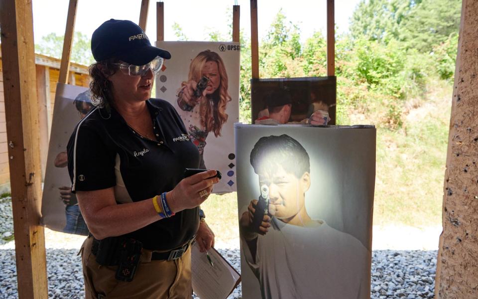 Course instructor Angela Armstrong examines a target for fresh bullets holes inside the Life Fire House - Stephen Takacs for The Telegraph