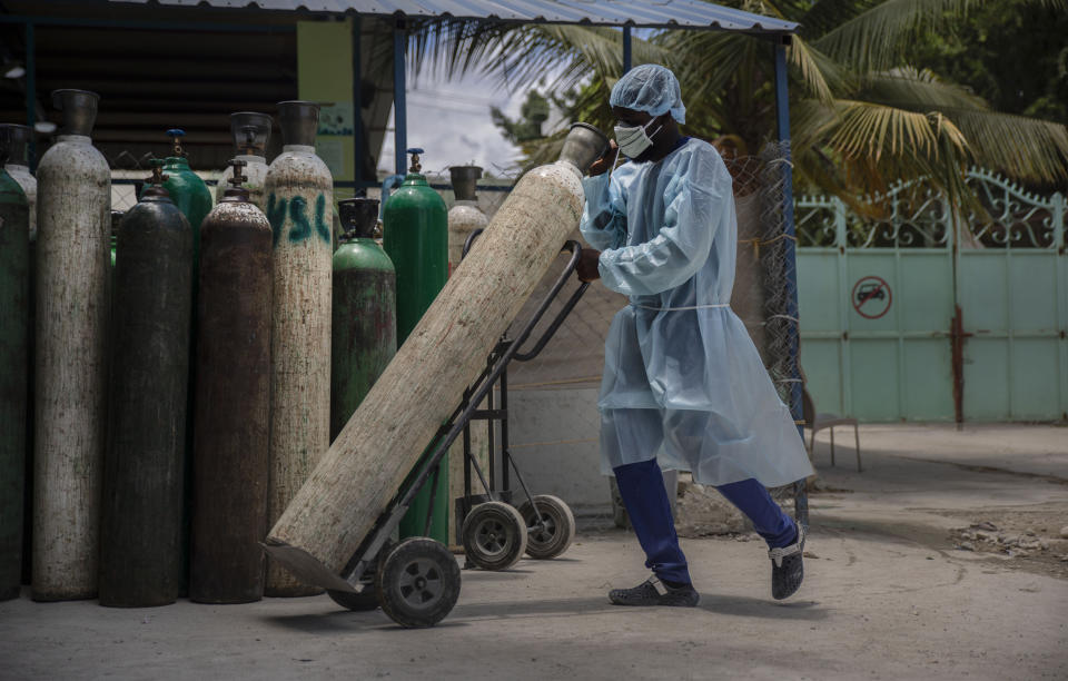 FILE - In this June 5, 2021, file photo, a hospital employee wearing protective gear transports oxygen tanks in Port-au-Prince, Haiti. In Haiti, hospitals turned away patients as the country awaits its first shipment of vaccines. Haiti received its first delivery of vaccines on July 15 after months of promises — 500,000 doses for a population over 11 million. (AP Photo/Joseph Odelyn, File)