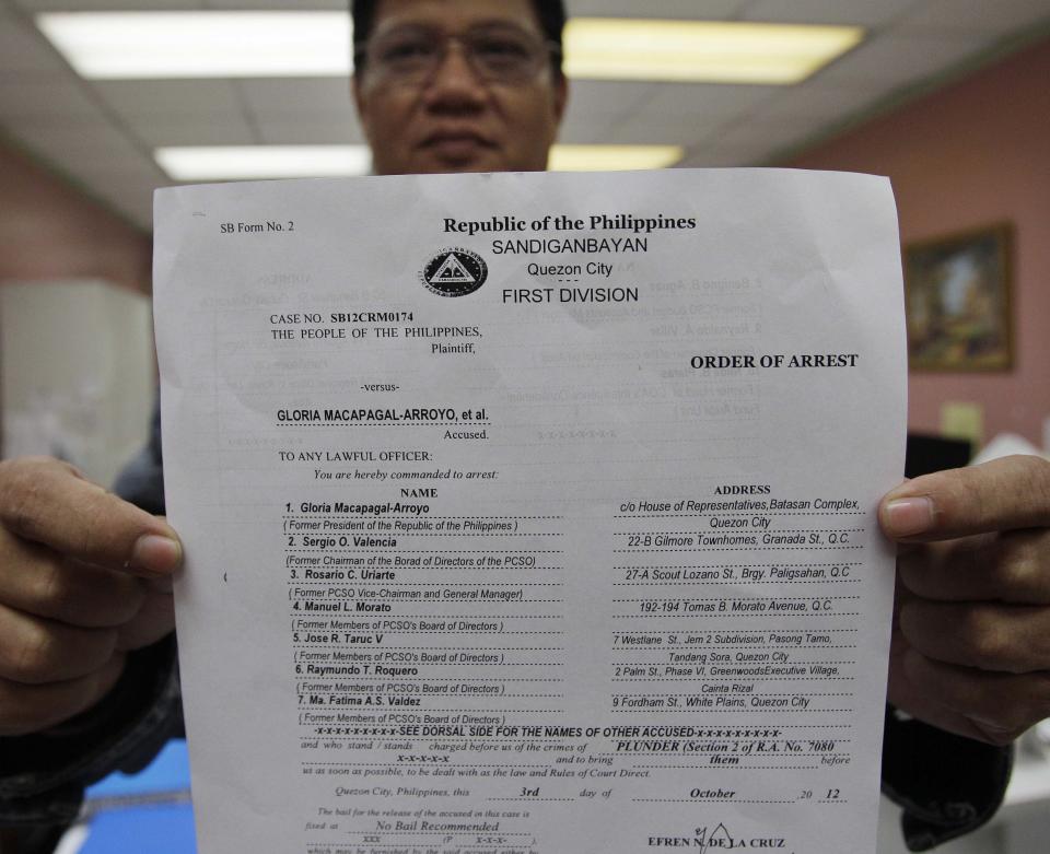 Sandiganbayan Executive Assistant Florecal Sebastian shows a copy of the Order of Arrest to former Philippine President Gloria Macapagal Arroyo at the Sandiganbayan anti-graft court in suburban Quezon City, north of Manila, Philippines, Thursday Oct. 4, 2012. The Philippine court has issued an order to arrest Arroyo on charges of plunder for allegedly misusing state lottery funds during her last years in office. (AP Photo/Aaron Favila)
