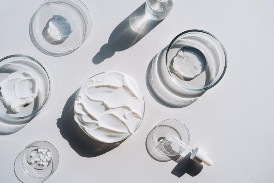 Background cosmetics laboratory concept photo research in flat lay style made with many petri dishes containing different cosmetic products and a glass bottle containing facial serum and a pipette on gray background