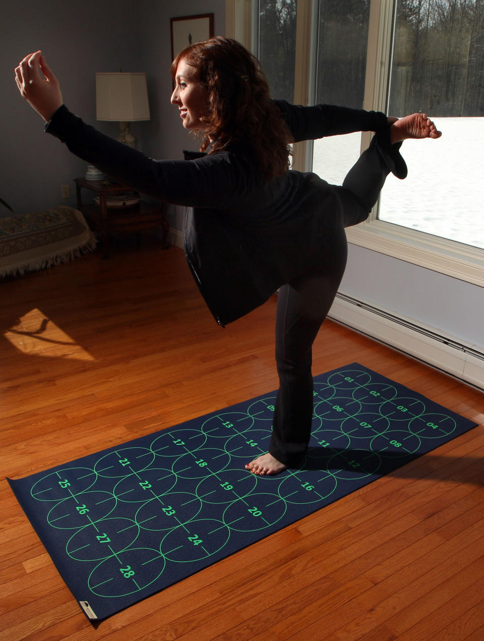 In this March 7, 2014 photo, Elizabeth Morrow poses on her specially designed Yoga by Numbers mat in Bow, N.H. The mat gives true yoga beginners a step-by-step roadmap to learn poses at their own pace. (AP Photo/Jim Cole)