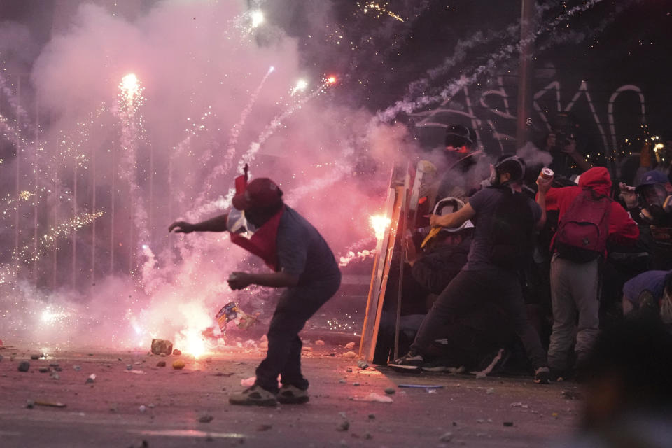 Anti-government protesters take refuge behind shields as police launch tear gas, in Lima, Peru, Saturday, Jan. 28, 2023. Protesters are seeking immediate elections, Boluarte's resignation, the release of ousted President Pedro Castillo and justice for protesters killed in clashes with police. (AP Photo/Martin Mejia)