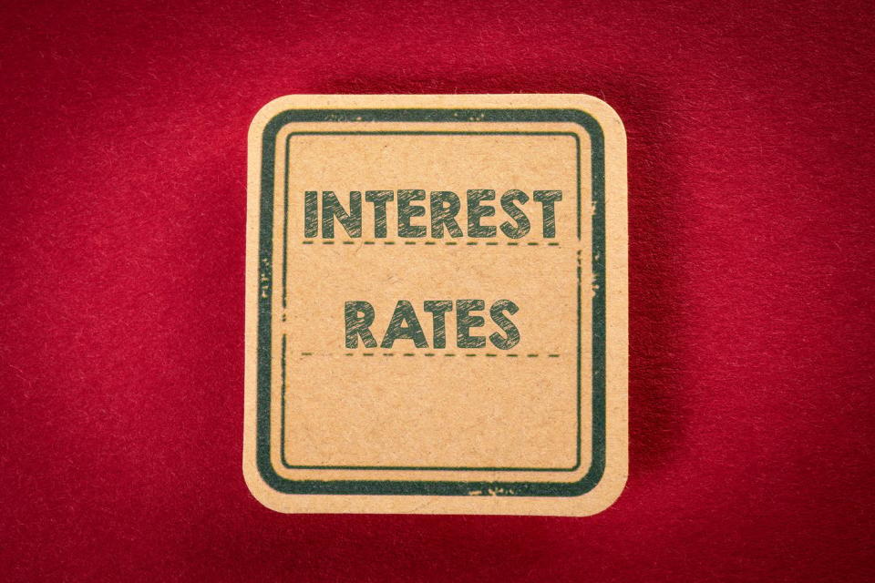 The words Interest Rates written on a sign  against a red background.