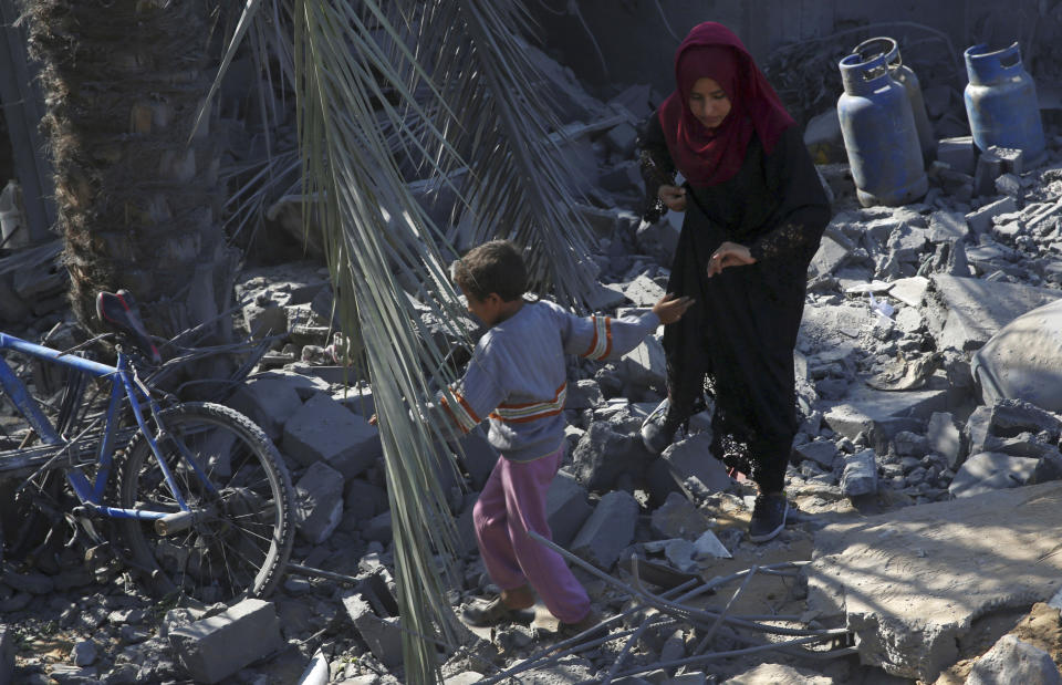 Palestinians walk amid the rubble of their family house following overnight Israeli missile strikes, in Al-Qarara, east of Khan Younis, southern Gaza Strip, Thursday, Nov. 14, 2019. (AP Photo/Adel Hana)