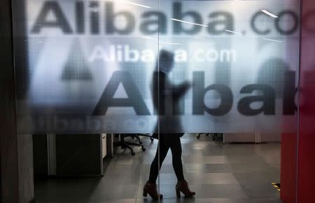 An employee is seen behind a glass wall with the logo of Alibaba at the company's headquarters on the outskirts of Hangzhou, Zhejiang province, April 23, 2014. REUTERS/Chance Chan/File Photo