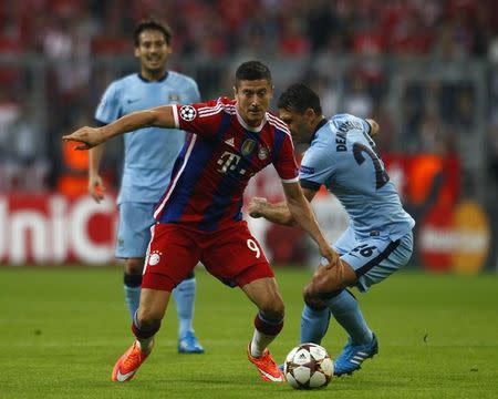 Bayern Munich's Robert Lewandowski runs the ball past Manchester Martin Demichelis (R) during their Champions League group E match in Munich September 17, 2014. REUTERS/Michaela Rehle