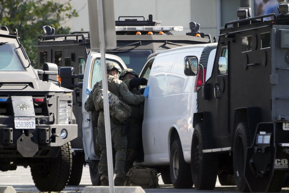 Members of a SWAT team enter a van and look through its contents in Torrance Calif., Sunday, Jan. 22, 2023. An hours-long manhunt led police to surround and enter the van. Authorities say the suspect in a California dance club shooting that left multiple people dead, shot and killed himself. (AP Photo/Damian Dovarganes)