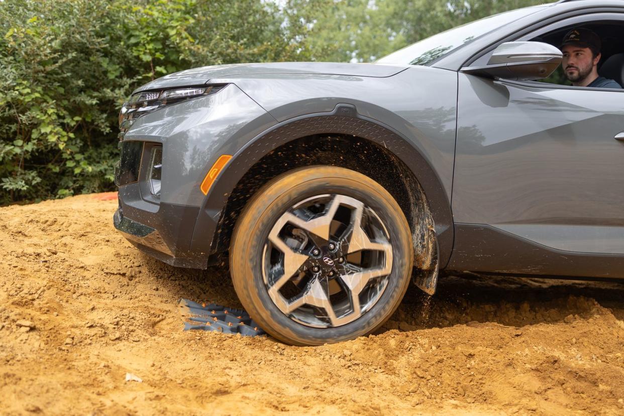 man driving in sand over a traction board to break free from the sand trap