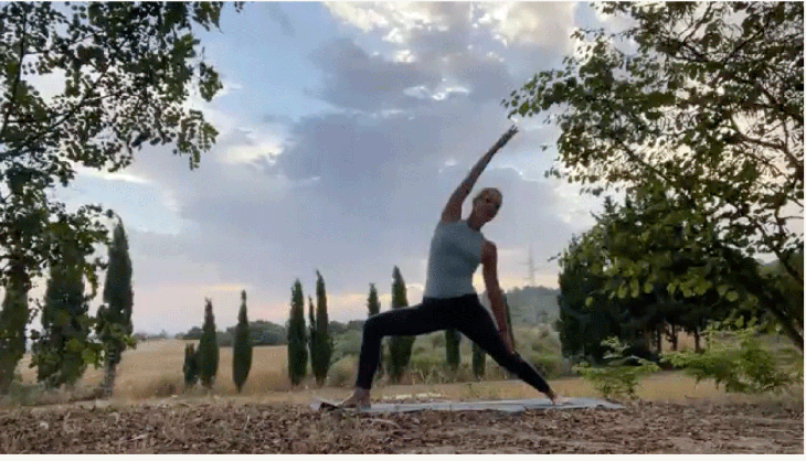 Woman practicing yoga outside at sunrise in Reverse Warrior