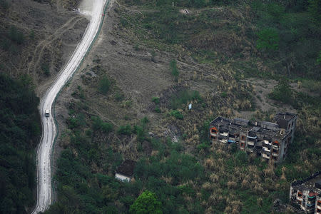 A vehicle drives past apartment blocks destroyed in a landslide caused by the 2008 Sichuan earthquake, at the foot of a mountain in the city of Beichuan, Sichuan province, China, April 4, 2018. REUTERS/Jason Lee