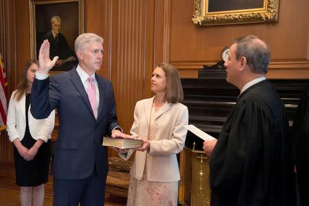 Chief Justice of the United States John Roberts (R) administers the constitutional oath to judge Neil Gorsuch, as his wife Louise Gorsuch holds the bible during a private ceremony at the Supreme Court in Washington, U.S., April 10, 2017. Courtesy Supreme Court of the United States/Handout via REUTERS