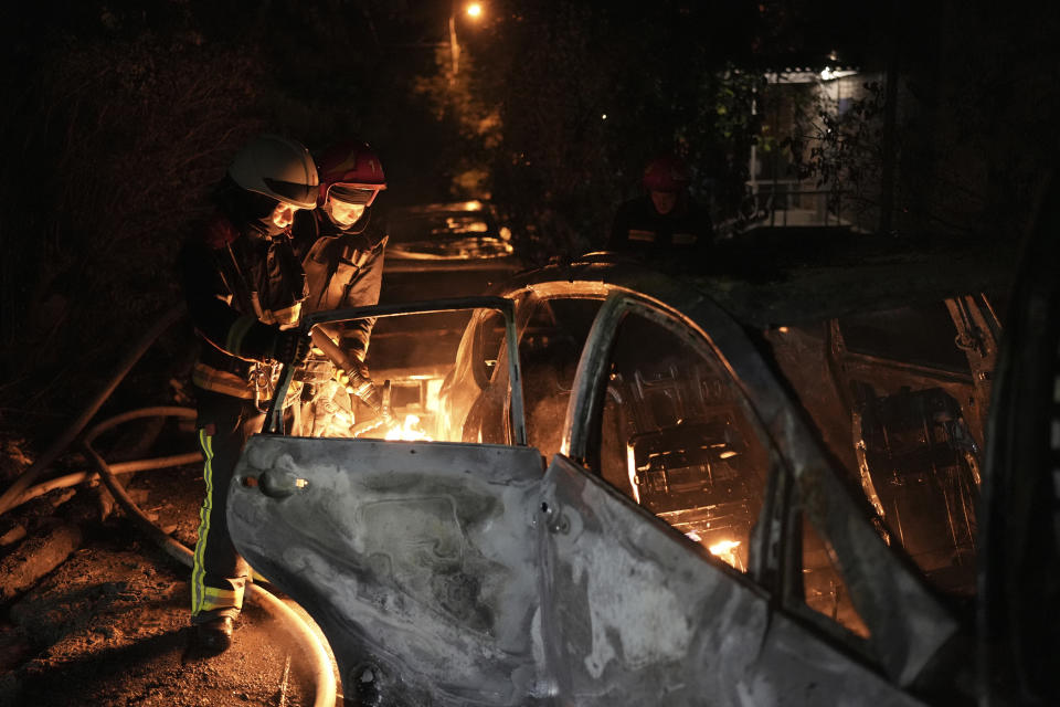 Socorristas tratan de apagar un auto que se incendió por la caída de escombros tras un ataque aéreo ruso en el distrito de Pecherskyi, en Kiev, Ucrania, el martes 30 de mayo de 2023. (AP Foto/Roman Hrytsyna)