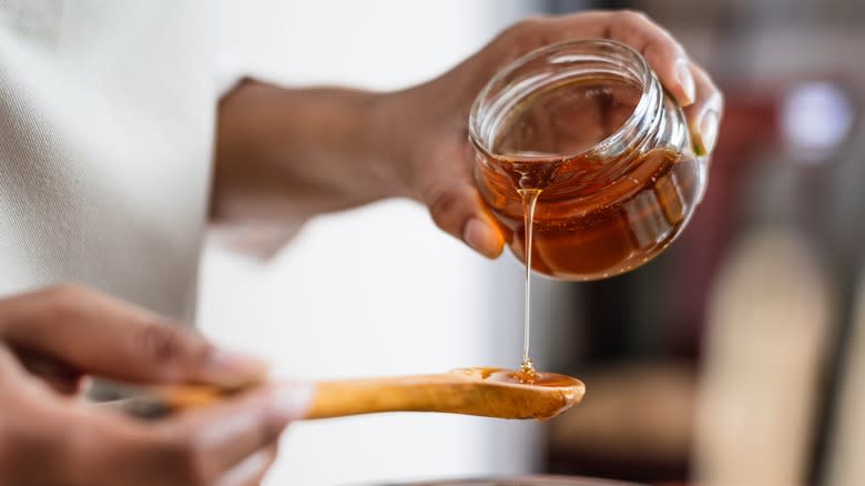 pouring honey out of jar into spoon