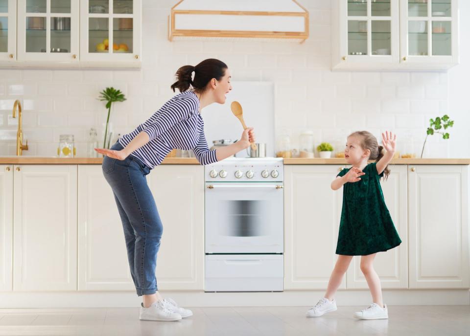 happy mom and daughter singing in the kitchen