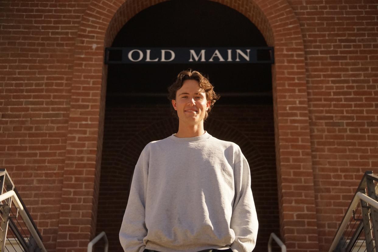 Aidan Pettit-Miller, 23, a public health student at the University of Arizona, stands in front of the Old Main building at the University of Arizona main campus in Tucson on Thursday, Dec. 8, 2022.