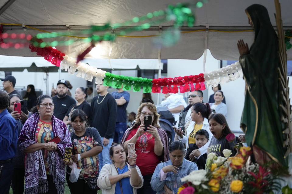 Devotees pray and take pictures in front of a figure of the Virgin of Guadalupe during a festival celebrating one of several apparitions of the Virgin Mary witnessed by an indigenous Mexican man named Juan Diego in 1531, at St. Ann Mission in Naranja, Fla., Sunday, Dec. 10, 2023. For this mission church where Miami's urban sprawl fades into farmland and the Everglades swampy wilderness, it's the most important event of the year, both culturally and to fundraise to continue to minister to the migrant farmworkers it was founded to serve in 1961. (AP Photo/Rebecca Blackwell)