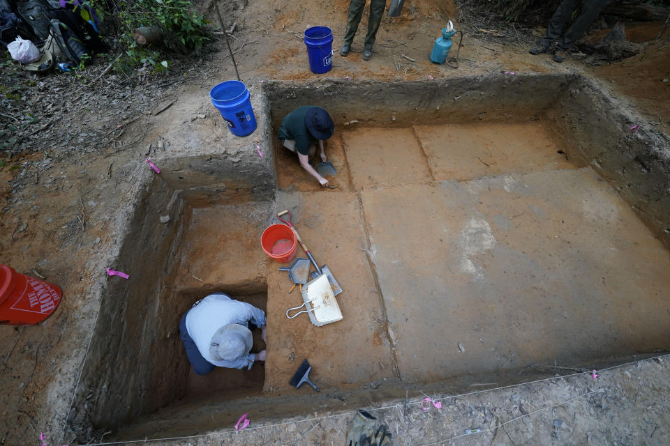 Gray Tarry, bottom left, an archeological field technician for the University of Louisiana at Lafayette, digs on an archeological excavation site in Kisatchie National Forest, La., Wednesday, June 7, 2023. This summer, archaeologists have been gingerly digging up the ground at the site in Vernon Parish to unearth and preserve the evidence of prehistoric occupation. The site was found by surveyors in 2003, according to the U.S. Forest Service. Hurricanes Laura and Delta uprooted trees and exposed some of the artifacts. Further damage has been done by looters making unauthorized digs. Forest officials say the site shows evidence of generations of people living in the area going back 12,000 years. (AP Photo/Gerald Herbert)