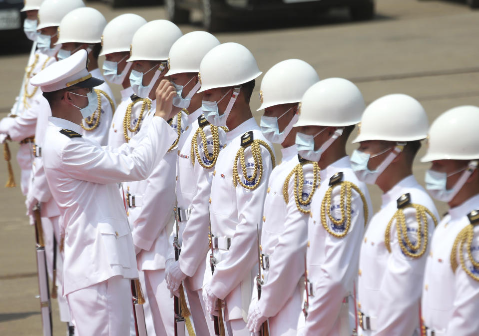 A Taiwan Navy honor guard captain adjusts team member's face mask during a launch ceremony for its first indigenous amphibious transport dock in Kaohsiung, southern Taiwan, Tuesday, April 13, 2021. (AP Photo/Chiang Ying-ying)