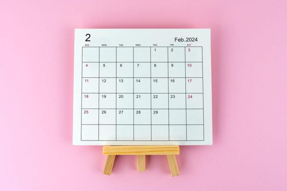 february 2024 calendar on wood easel, against pink background
