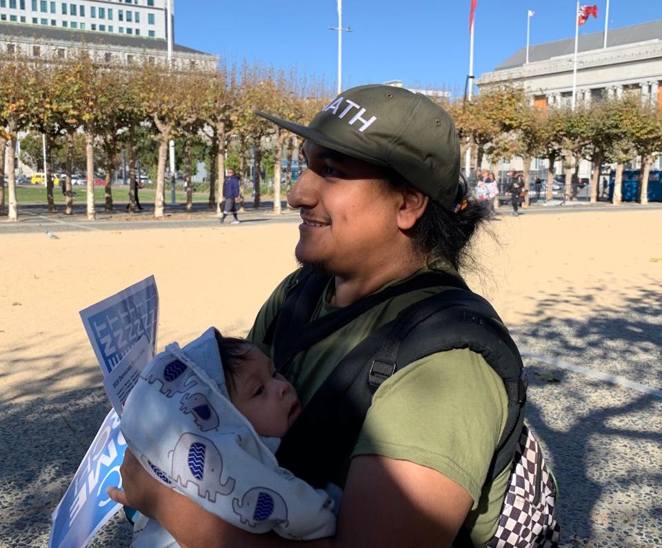 Milo Alvarez and his infant son attend a rally for Democratic presidential candidate Andrew Yang. Alvarez, who fixes scooters, says he likes Yang's ideas about a universal basic income, and doesn't feel that candidates should target him specifically as a Latino voter but rather as someone who cares about a broad range of issues.