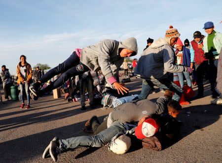 A migrant, part of a caravan of thousands traveling from Central America en route to the United States, jumps on his friends as they play together at a makeshift camp at a gas station where the migrants wait for buses in Navojoa, Mexico November 16, 2018. REUTERS/Kim Kyung-Hoon