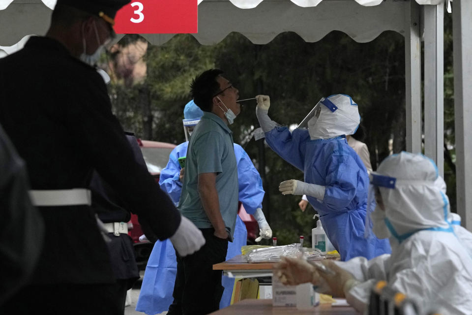 A resident gets swabbed during a mass COVID test, Wednesday, April 27, 2022, in Beijing. Workers put up fencing and police restricted who could leave a locked-down area in Beijing on Tuesday as authorities in the Chinese capital stepped up efforts to prevent a major COVID-19 outbreak like the one that has all but shut down the city of Shanghai. (AP Photo/Ng Han Guan)