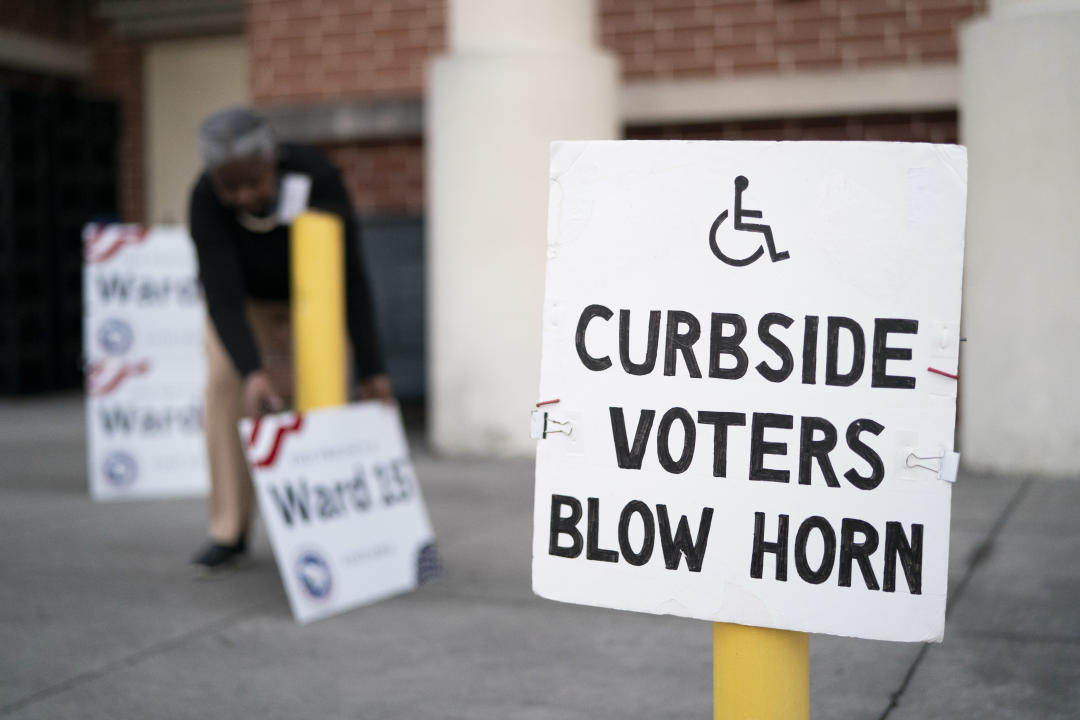 A poll worker adjusts signs at Dreher High School in Columbia, S.C.