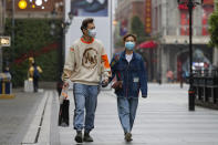 In this photo released by Xinhua News Agency, a couple wearing protective masks to prevent the new coronavirus outbreak walk on a re-opened commercial street in Wuhan in central China's Hubei province on Monday, March 30, 2020. Shopkeepers in the city at the center of China's virus outbreak were reopening Monday but customers were scarce after authorities lifted more of the anti-virus controls that kept tens of millions of people at home for two months. (Shen Bohan/Xinhua via AP)