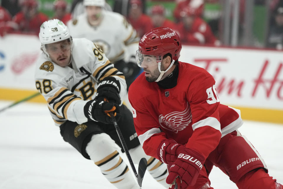 Detroit Red Wings defenseman Jake Walman (96) controls the puck next to Boston Bruins right wing David Pastrnak during the first period of an NHL hockey game Saturday, Nov. 4, 2023, in Detroit. (AP Photo/Carlos Osorio)